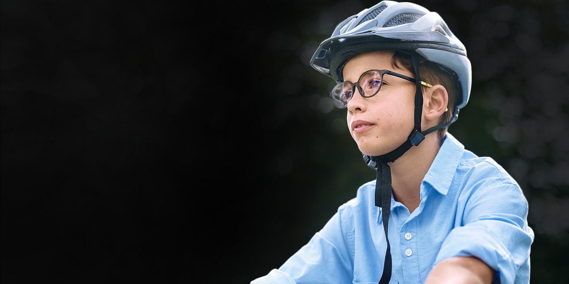 A young boy wearing glasses and a helmet appears to be riding his bike.
