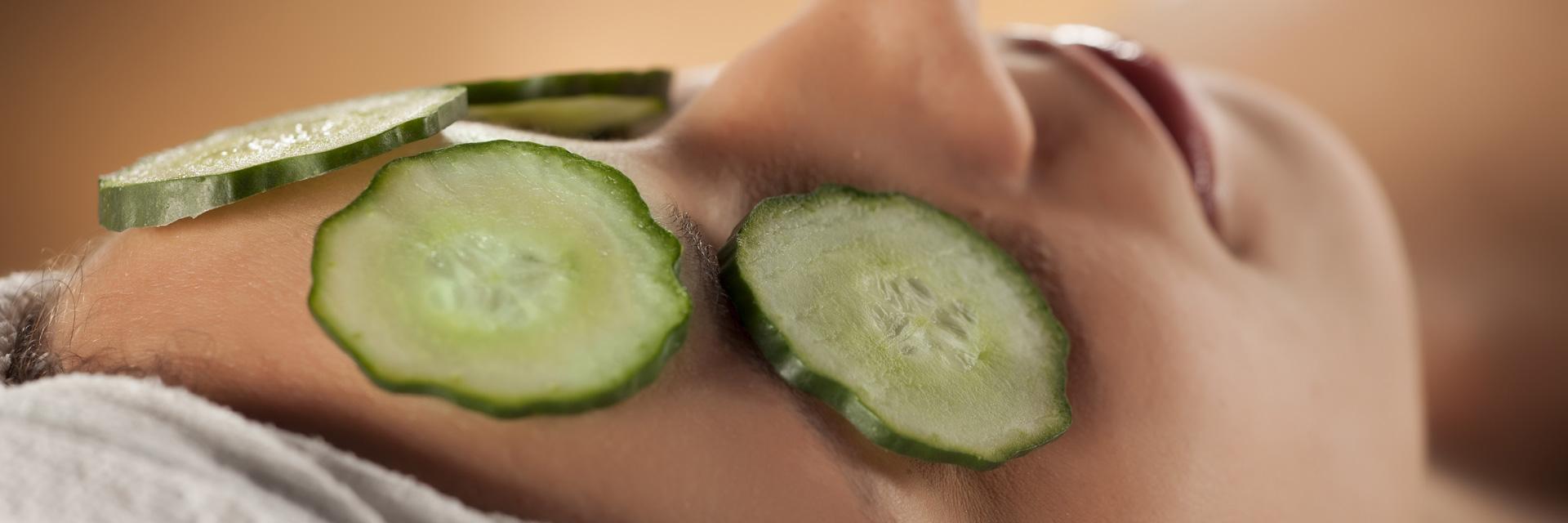 young woman with a towel on her head and cucumbers on her eyes