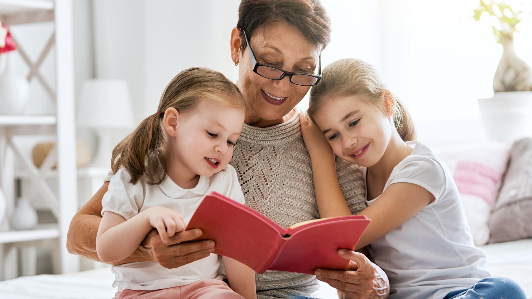Grandmother reading a book to granddaughters
