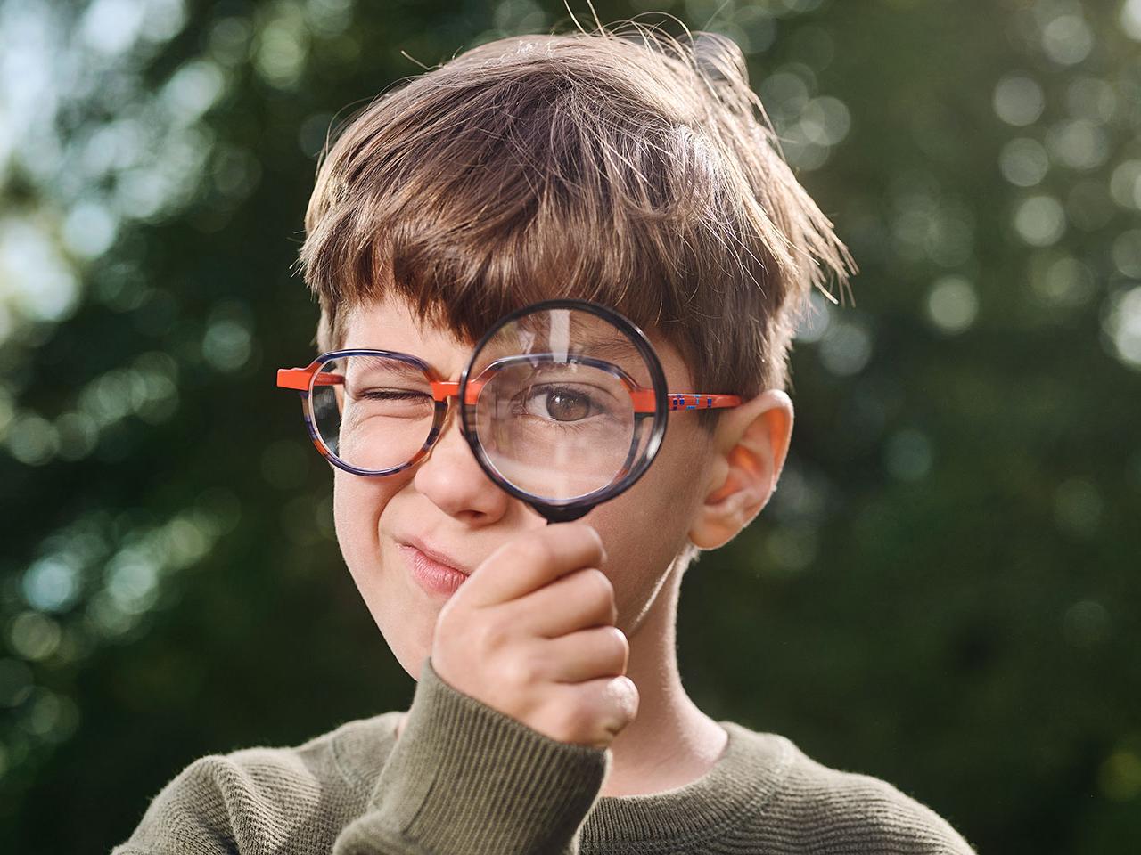 Boy with glasses using a magnifier 