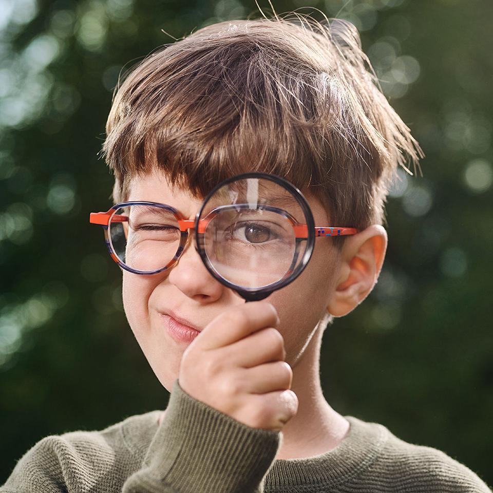 Boy with glasses using a magnifier 