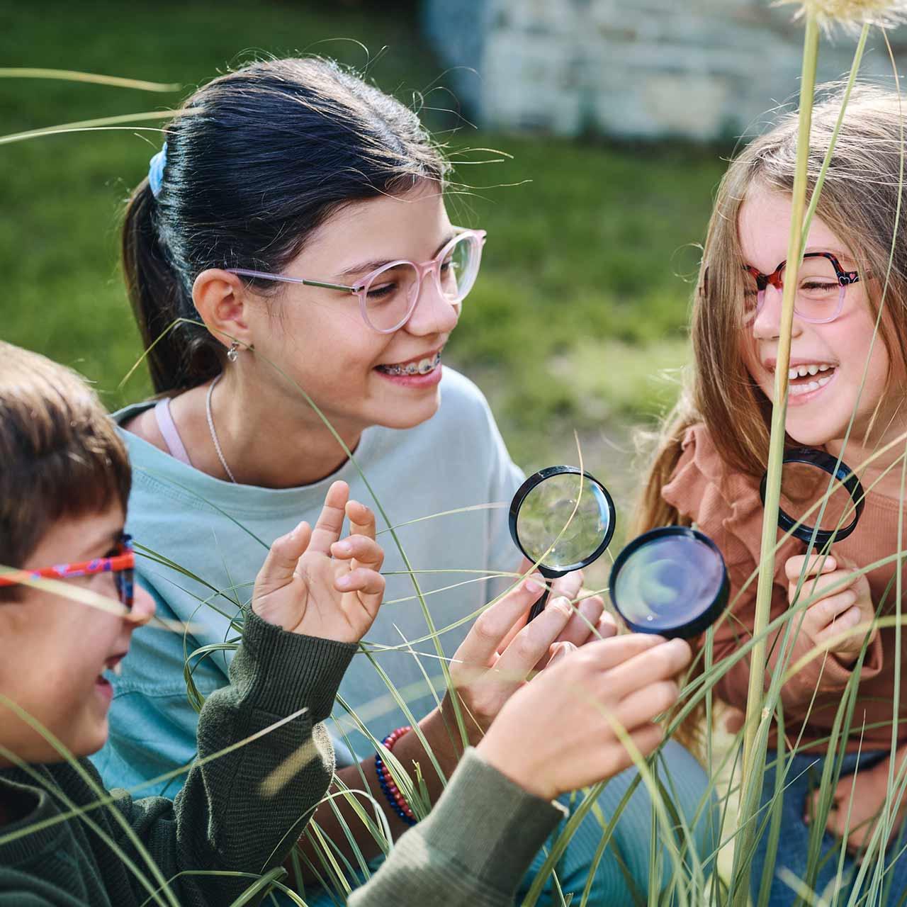 Group of children with glasses and magnifiers playing and laughing outside