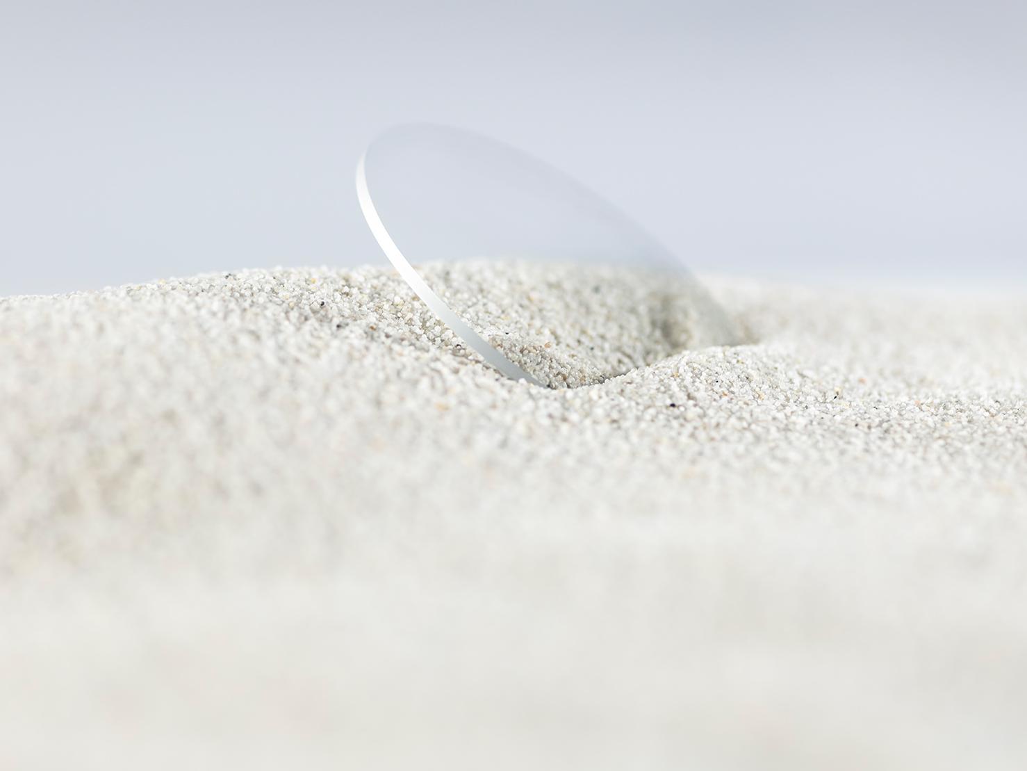 粗糙的沙子覆蓋具有耐用鍍膜的蔡司鏡片，但鏡片仍然沒有划痕。