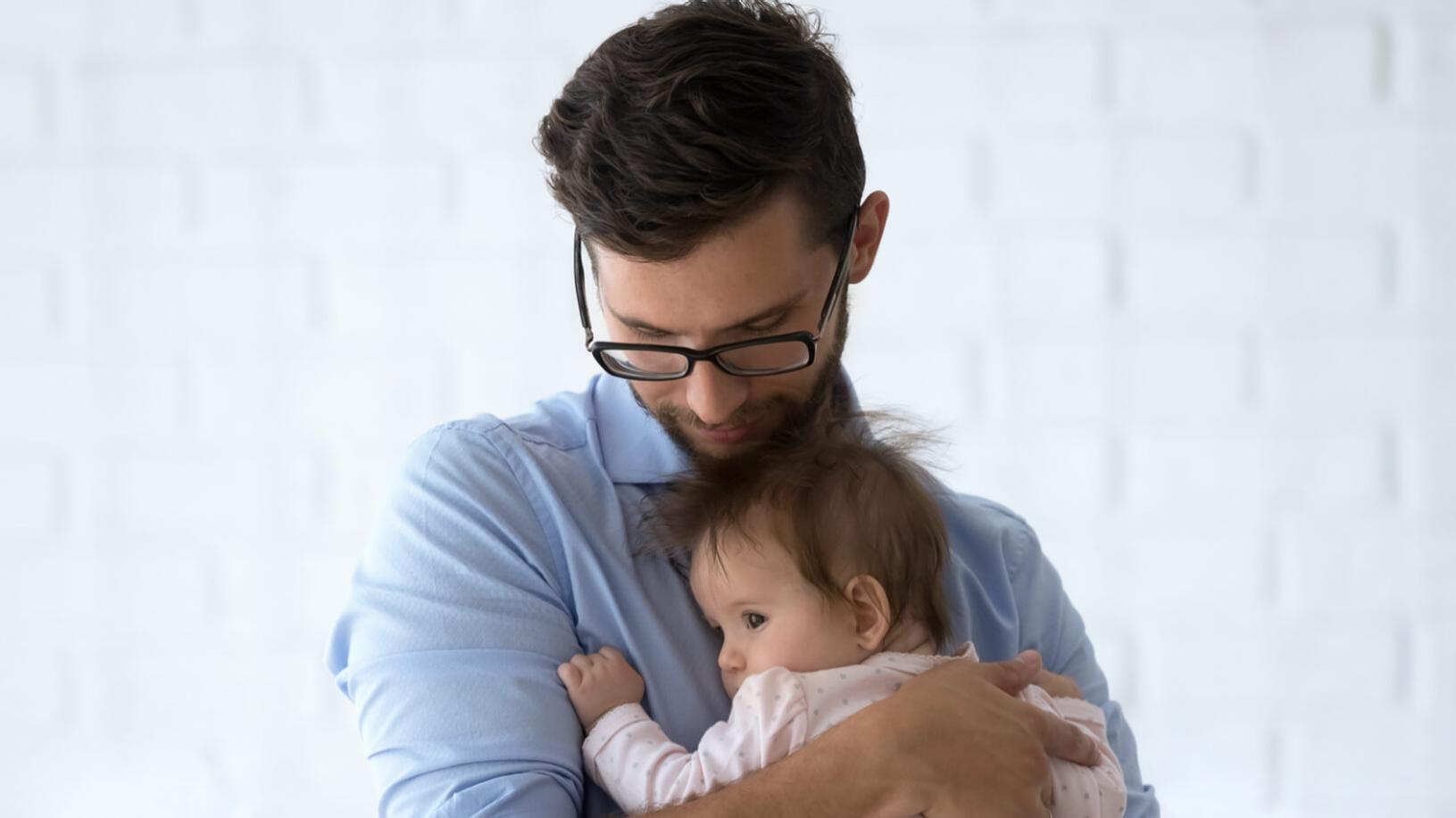 A shortsighted man wearing glasses holding a toddler.