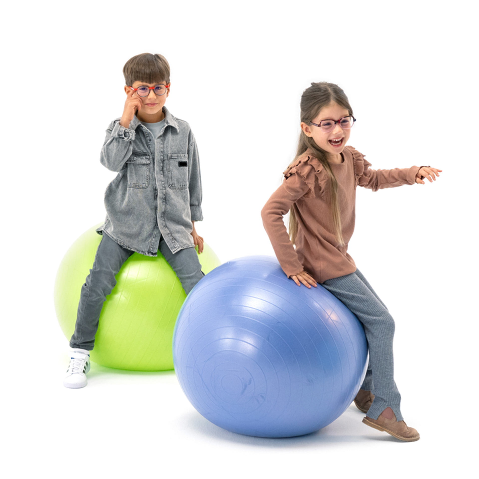 兩位分別戴著眼鏡的男孩和女孩，開心的拍體操球玩 。