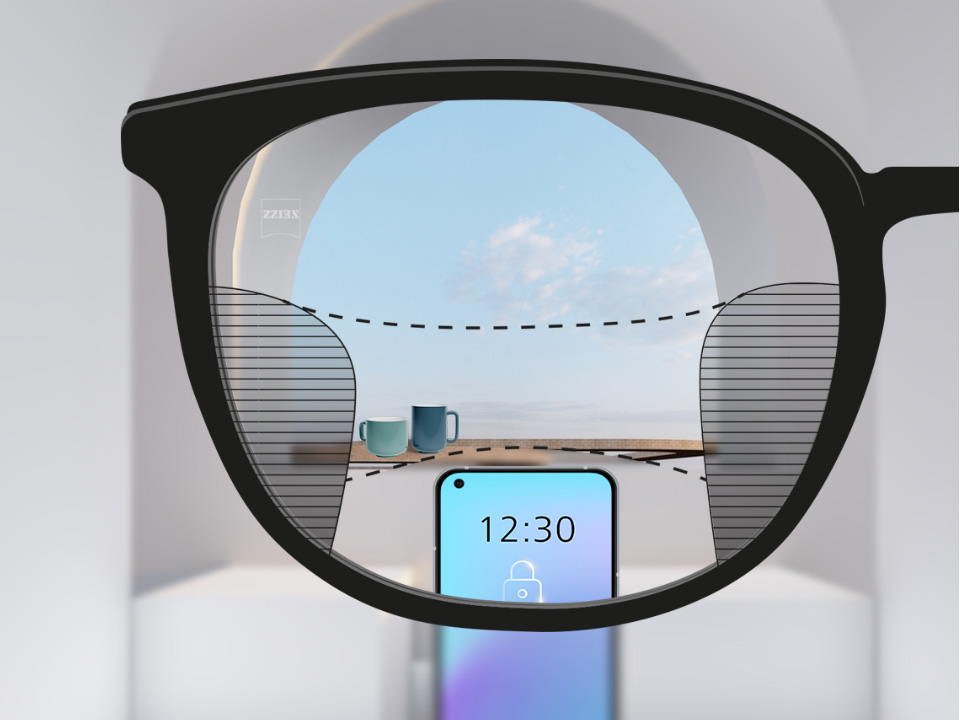 從蔡司 SmartLife 漸進鏡片看到的視野：背景有一部智能手機和杯子，鏡片完全清晰，但左右兩側均有細長模糊區域。